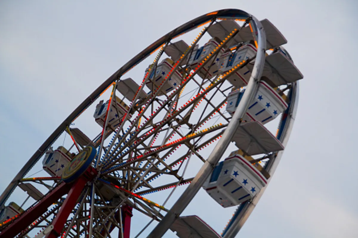 A vibrant nighttime scene featuring the Ferris wheel at The Island, illuminated with colorful lights against the evening sky. The carnival-like atmosphere is filled with the anticipation of fun and shared experiences, with the Ferris wheel acting as a beacon for local entertainment and romantic moments.