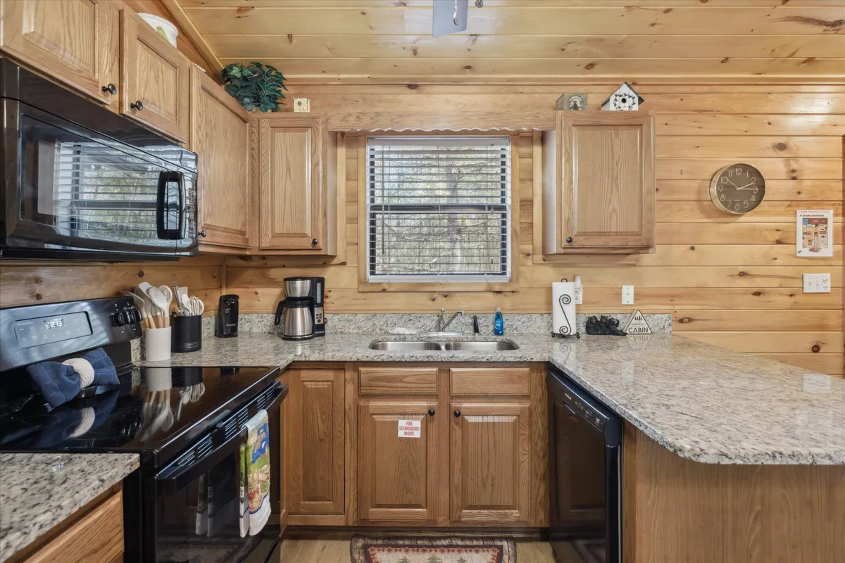 A close-up view of the kitchen area with rich wooden cabinetry, a granite countertop, a coffee maker ready for morning rituals, and a window with soft blinds. The space radiates warmth and welcome, perfect for preparing meals or enjoying quiet moments.